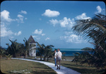 Walter W. S. Cook and another man walk along a path on North Cat Cay, Bahamas