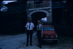 Two Men Standing in Front of a Red Car Parked Near the Barbados Museum
