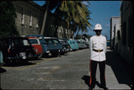 Royal Bahamas Police Force officer standing in front of parked cars