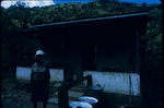 A woman standing in front of a house in Moore Town, Portland, Jamaica