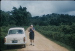 A man standing next to a car on a dirt road in Saint Ann, Jamaica