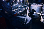 A steel pan maker looking at the surface markings on a steel pan instrument in Trinidad