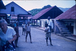 Adults and children gathered in the yard near buildings on a cocoa plantation in Trinidad