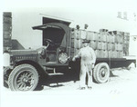Photograph of a Man Next to a Truck Packed with Orange Crates