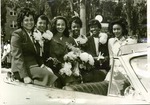 Homecoming Queen and attendants sit on car