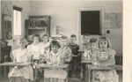 Ten children seated in classroom of first school, in converted wood church, c. 1946-47