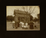 Group of Women, Men, and Children Standing in Front of House
