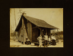 Men, Children, and Woman Standing in Front of House