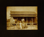 One Woman and Two Girls Standing with Baby in Front of House