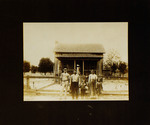One Woman, Two Men, and Three Children Standing in Front of House
