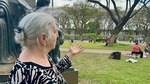 Woman enjoying a sunny day in Parque Los Andes, Buenos Aires while sharing a story with friends nearby by Wendy Howard