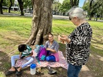 Two young people enjoy a sunny afternoon in Parque Los Andes while an older woman shares stories in Buenos Aires by Wendy Howard