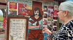 Woman interacts with Gauchito Gil mural at Santuario del Gauchito Gil in Parque Los Andes, Argentina by Wendy Howard