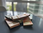 Currency in Buenos Aires street market showing stacks of banknotes on table with city backdrop by Wendy Howard