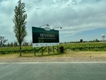 Welcome sign at the entrance of Mendoza Argentina surrounded by vineyards and open fields by Wendy Howard