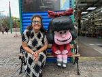 Colorful street art in Caminito with local resident posing beside iconic character sculpture by Wendy Howard