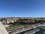 View over Lisbon from the Monument to the Discoveries showing boats, buildings, and green spaces in the distance by Wendy Howard