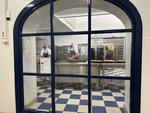 Bakers preparing pastries inside a Lisbon bakery seen through a blue arched window by Wendy Howard
