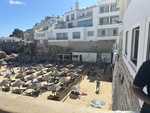 Beach scene showing visitors enjoying a sunny day in Cascais with umbrellas and nearby buildings in Portugal by Wendy Howard