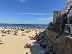 Sunny beach scene at Lisboa, Portugal with many sunbathers enjoying the warm weather by the coastline by Wendy Howard