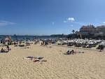 Sunny beach day in Lisbon with sunbathers enjoying the warm weather and clear skies by Wendy Howard