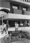 Library, sign and students outside entrance
