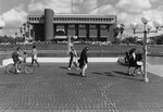 Library - students walk and bike in front of Reflecting Pond